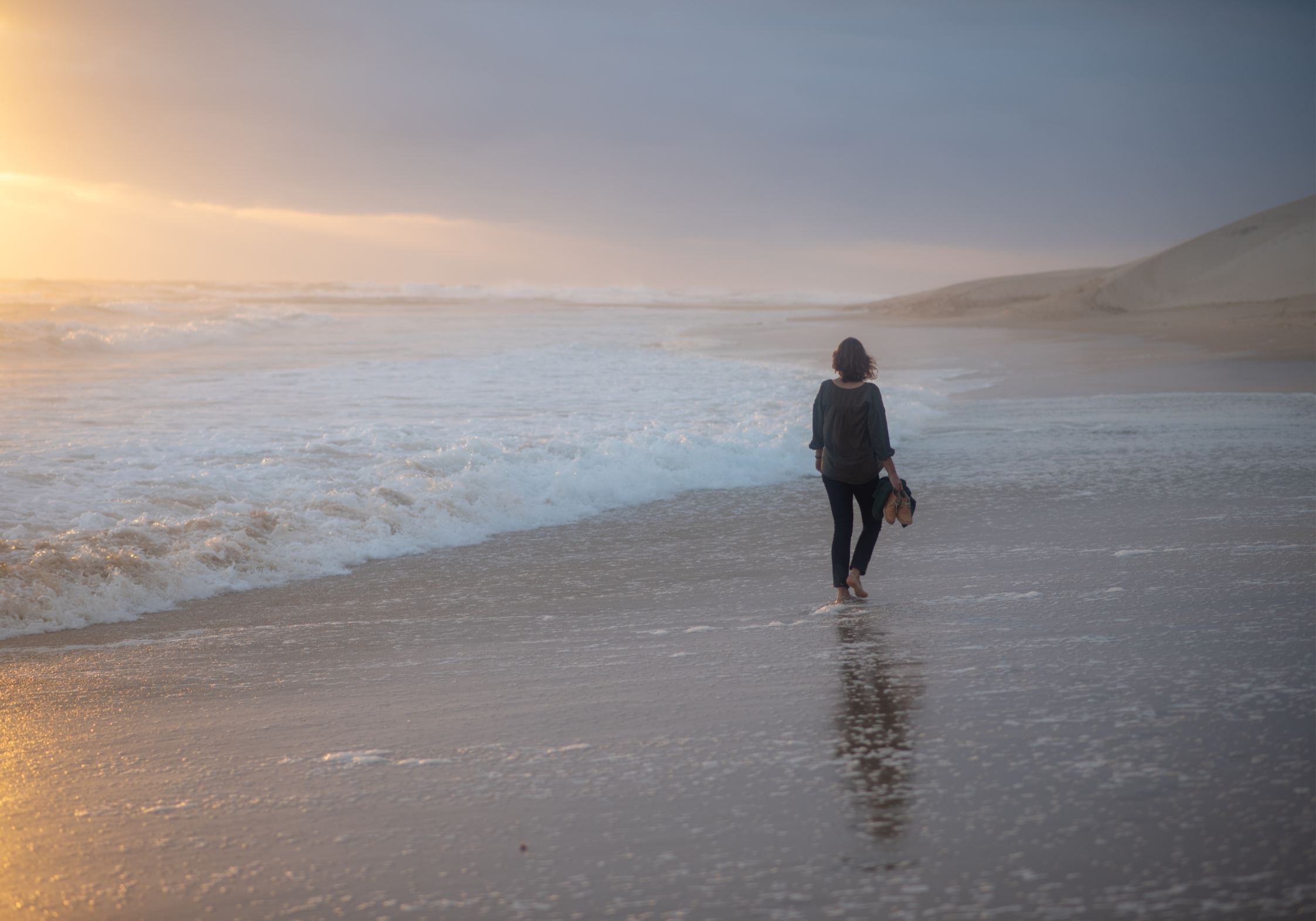 Midlife woman walking alone along a beach Empty nesting impact on a woman